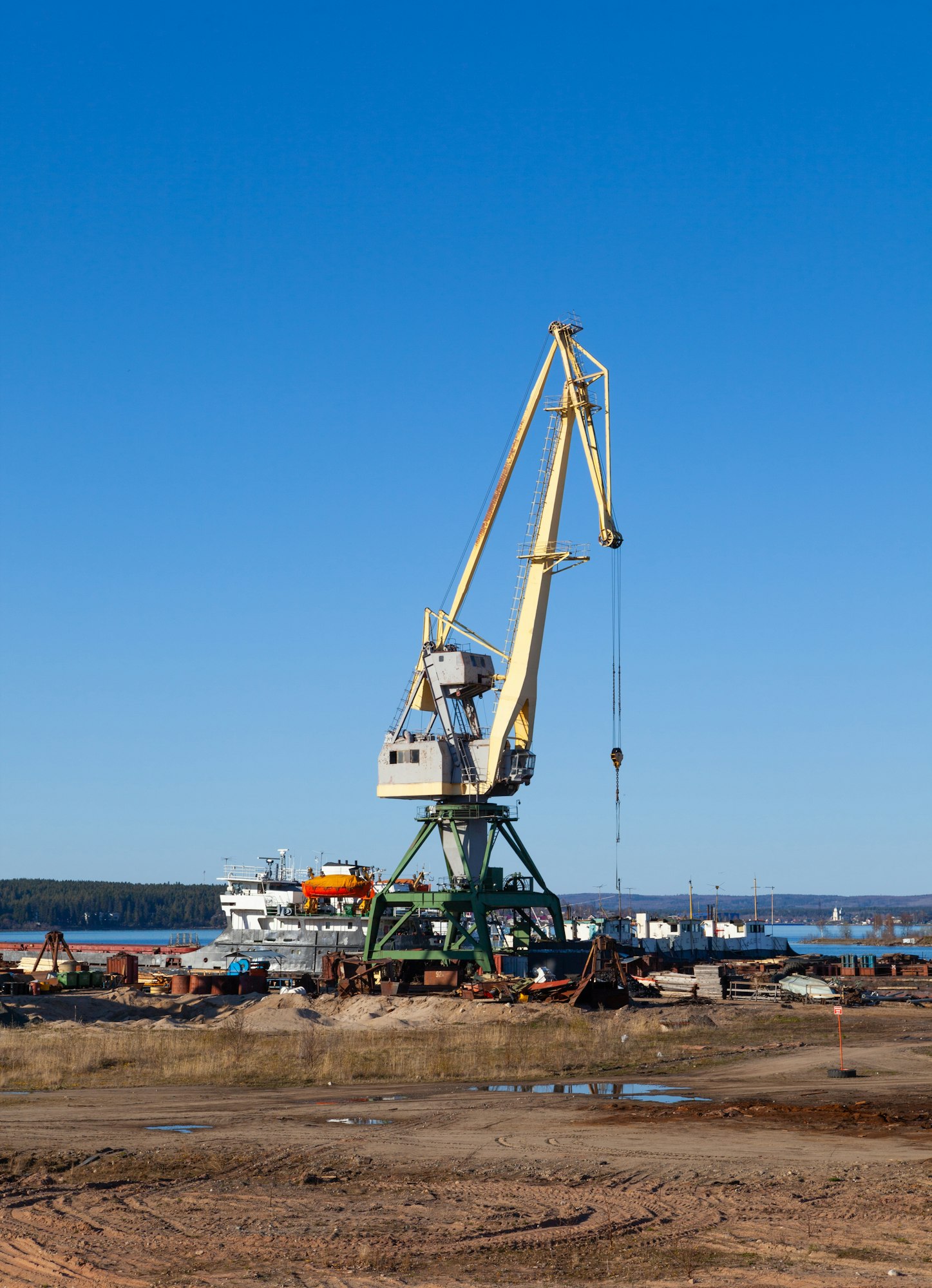 Crane in the port of machinery and forklifts to load and unload pallets on a sunny summer day