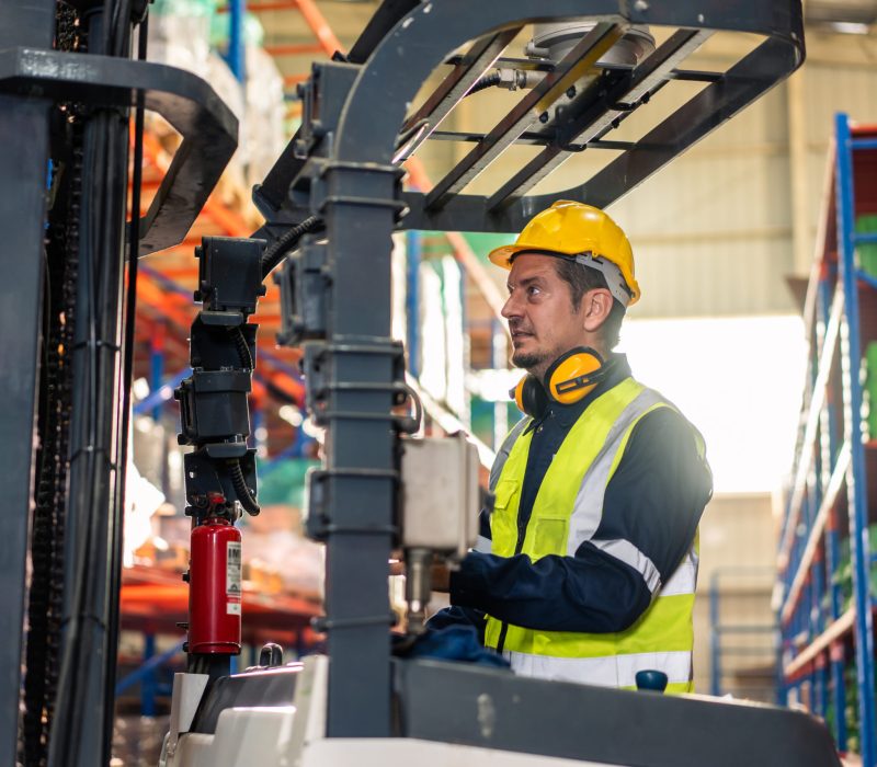 Caucasian attractive man industrial worker work in manufacturing plant. Professional male industry factory engineer wear helmet and processes orders and product at manufactory warehouse with happiness