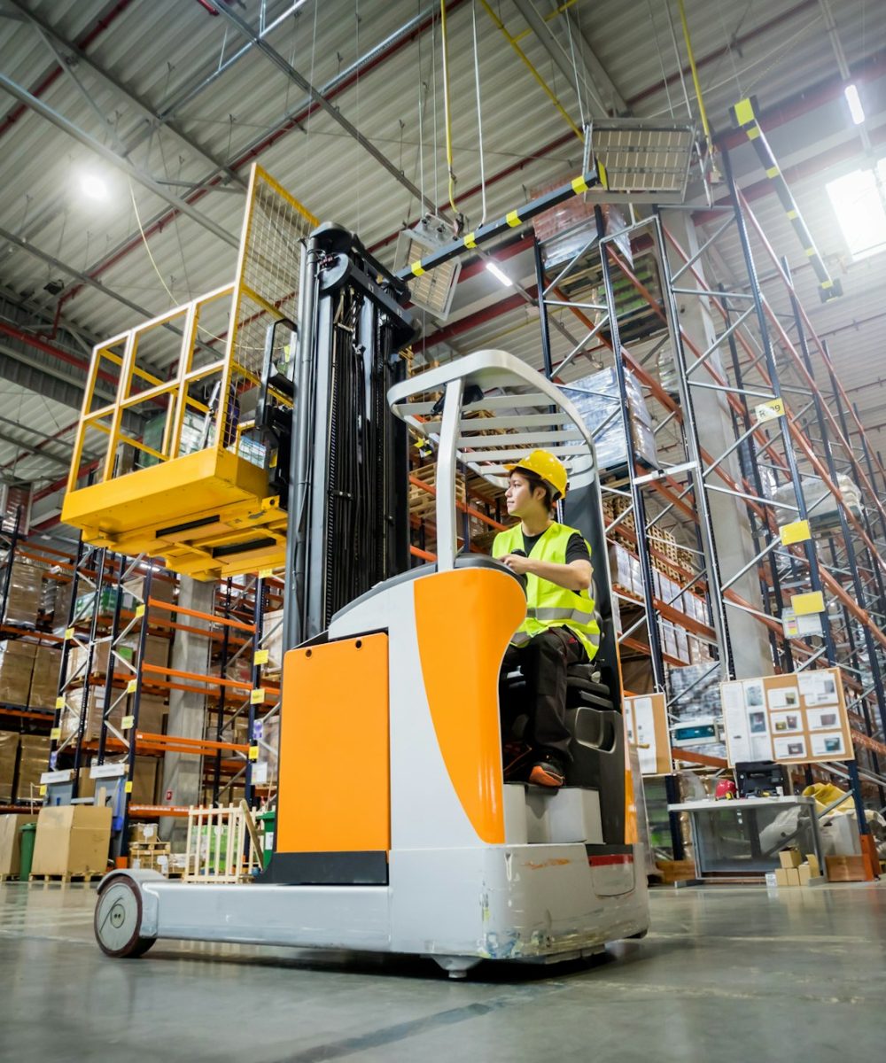 Forklift operator during work in large warehouse