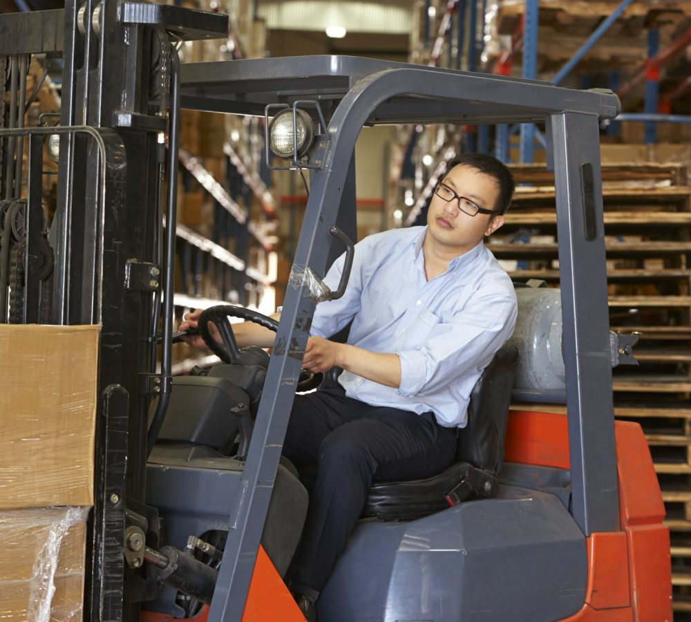 Man Driving Fork Lift Truck In Warehouse